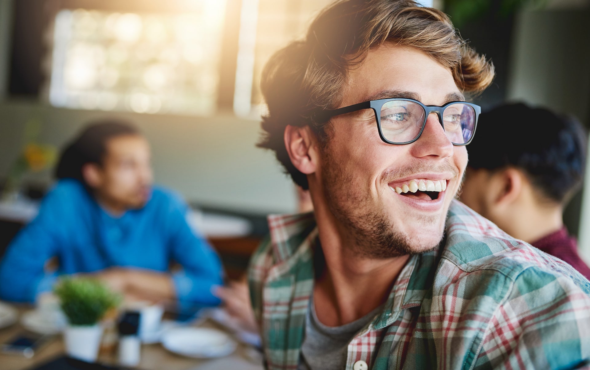 photo os guy with glasses looking back and laughing. Background is blurred